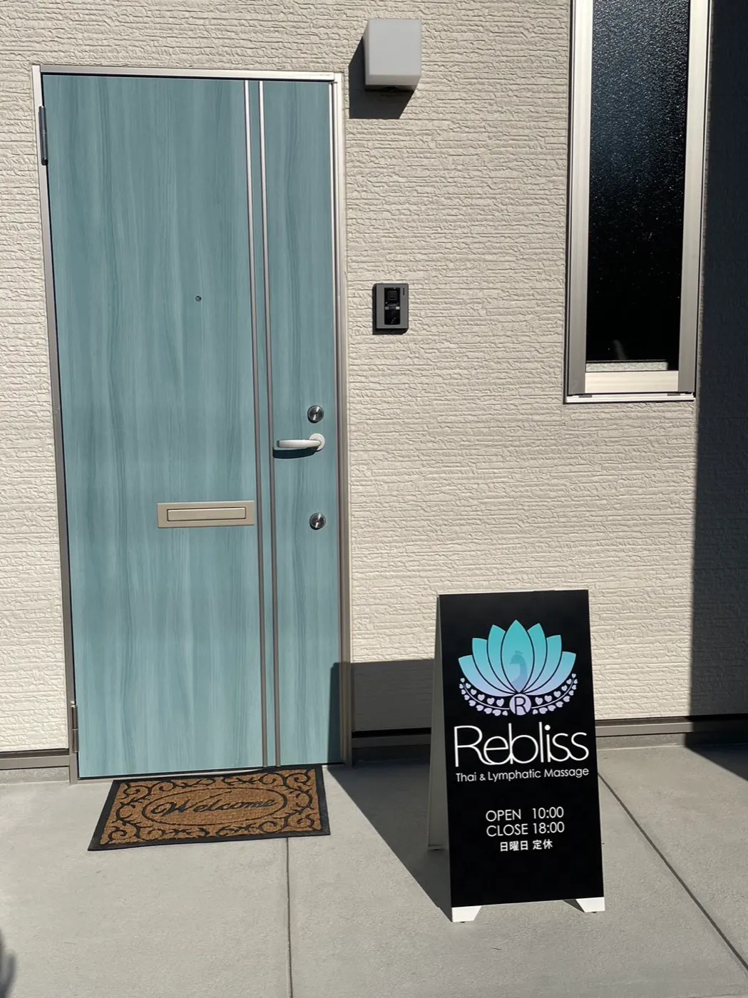 Rebliss 外観・入口（ティールの扉と看板が目印）